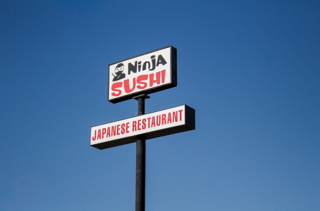 Pylon sign for Ninja Sushi in Yuma featuring high-impact Lexan faces and a bright LED retrofit for enhanced night visibility against a clear blue sky.
